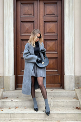 a lady wears a gray wrap coat with a gray mini skirt